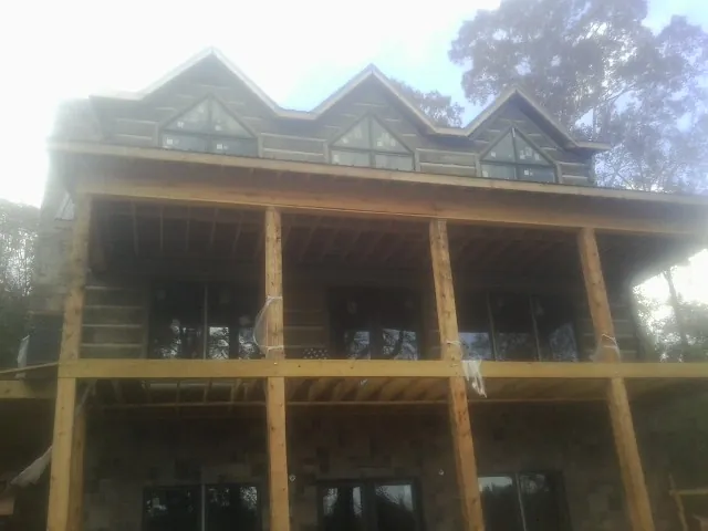 Dormers and porch framing on a large log home under construction — Roof Coating work by our crew in Dillard
