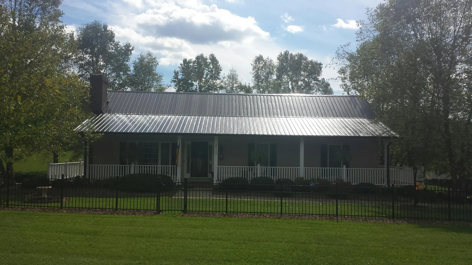 Gray metal roof on a brick ranch with a full width front porch — Gutter Guard Installation work by our crew in Dillard