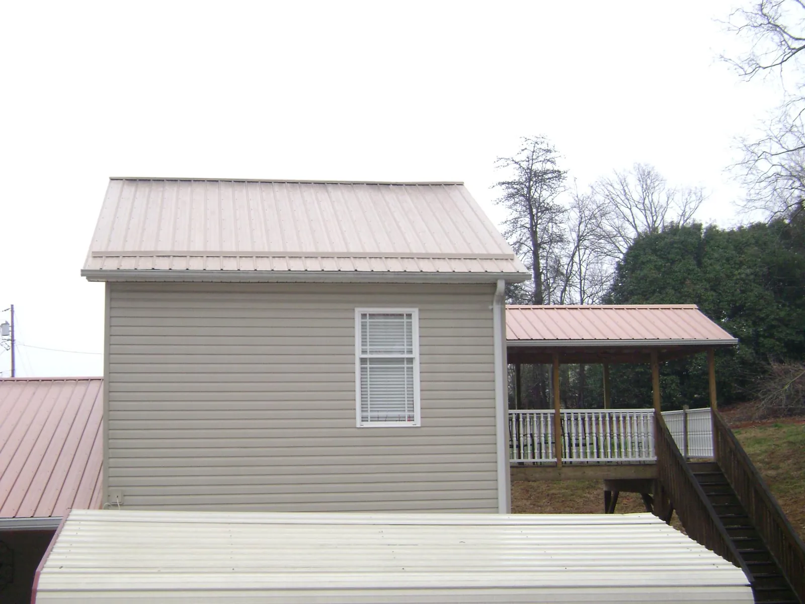 Tan metal roofs on a two story addition and attached porch, from a Roof Replacement job in Dillard