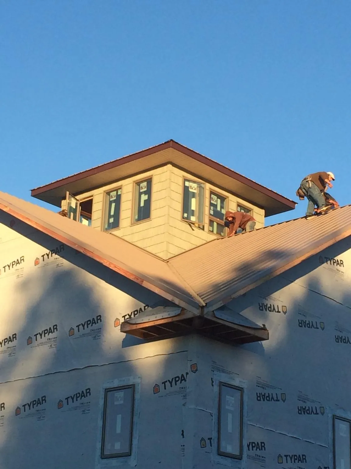 Roofers working around a rooftop cupola on a new metal roof at sunset — Roof Waterproofing in Dillard by Roofing Brothers
